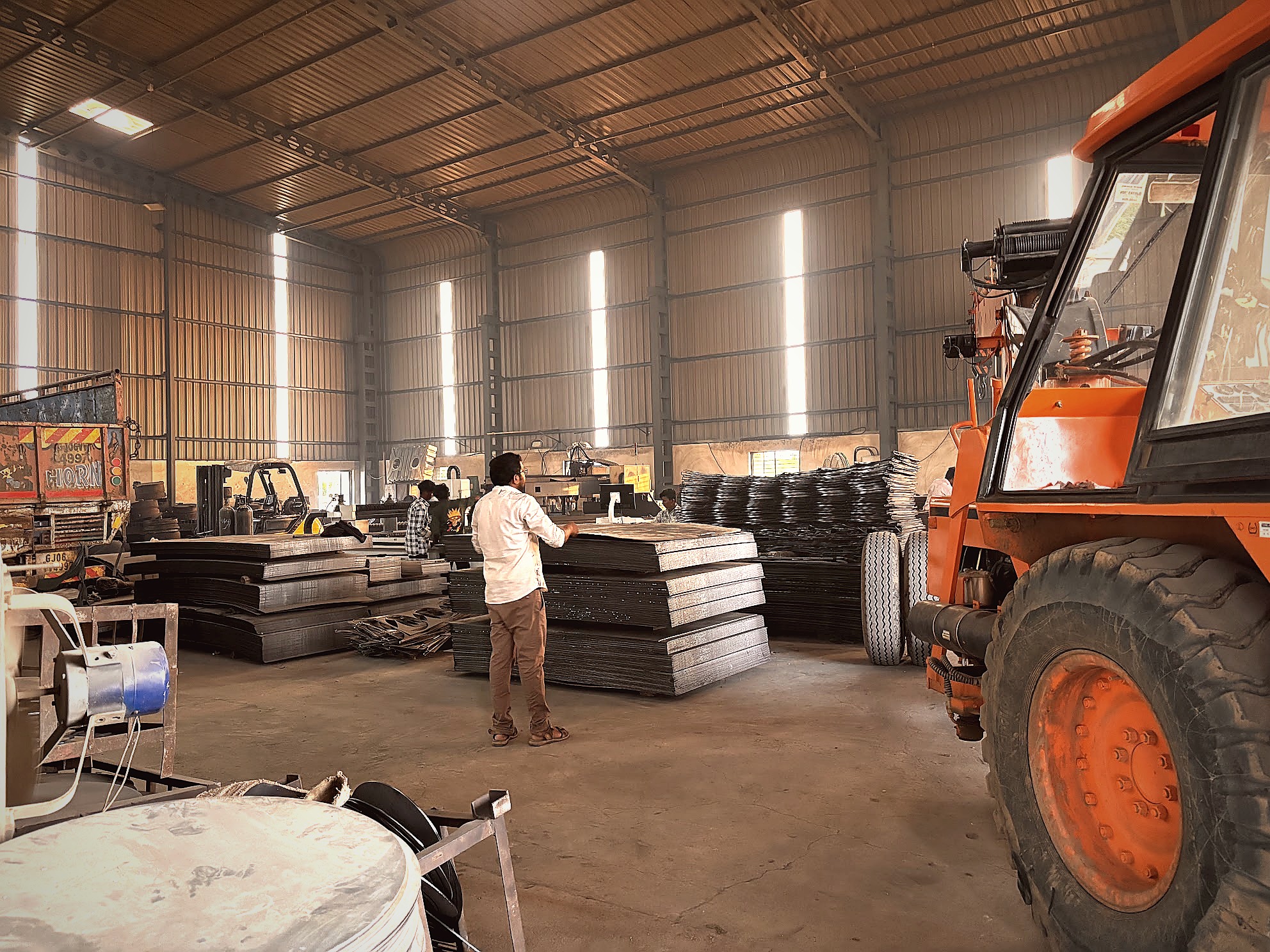 Raw steel coils and sheets in warehouse with forklift
