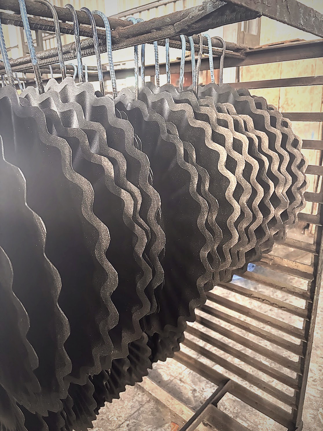 Wavy coulter blades hanging on drying rack after shot blast
